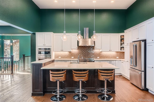 kitchen featuring light countertops, appliances with stainless steel finishes, hanging light fixtures, and a center island with sink