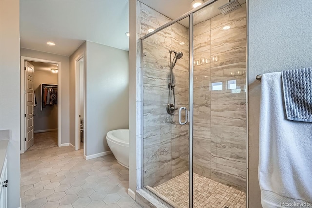 full bath with a stall shower, baseboards, tile patterned flooring, a walk in closet, and a freestanding bath