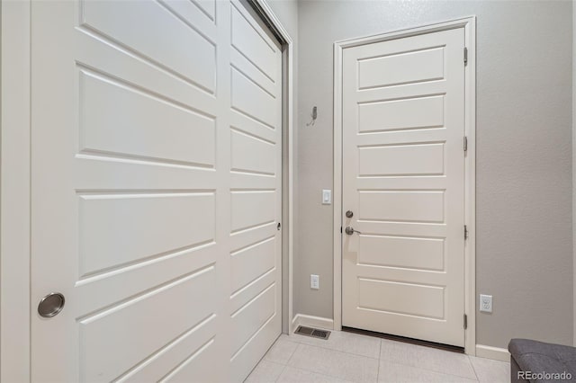 doorway with light tile patterned flooring, visible vents, and baseboards