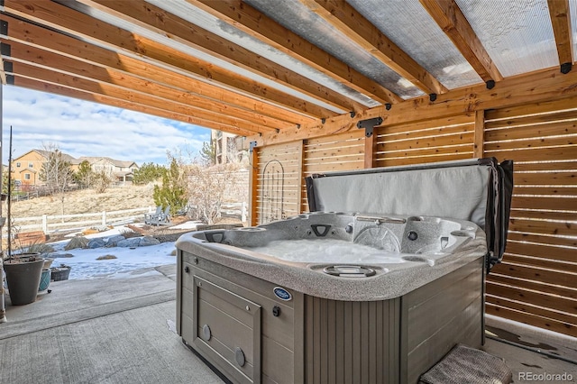 snow covered patio featuring a hot tub and fence