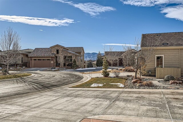 exterior space with concrete driveway, an attached garage, and a mountain view