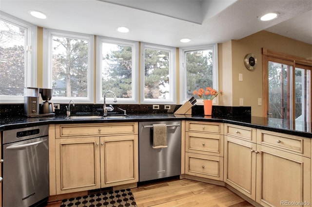 kitchen featuring dark stone countertops, sink, light hardwood / wood-style flooring, and stainless steel dishwasher