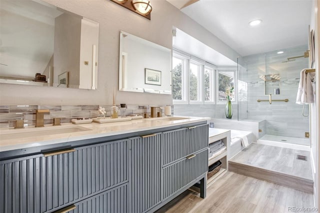 bathroom featuring vanity, hardwood / wood-style floors, decorative backsplash, and plus walk in shower