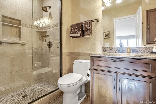 bathroom featuring vanity, an enclosed shower, tile walls, and toilet