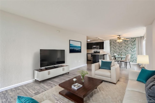 living room featuring ceiling fan and light hardwood / wood-style flooring