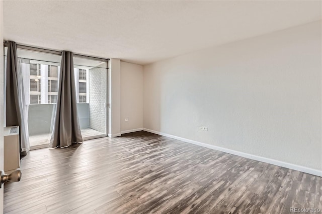 unfurnished room featuring a wall of windows and hardwood / wood-style floors