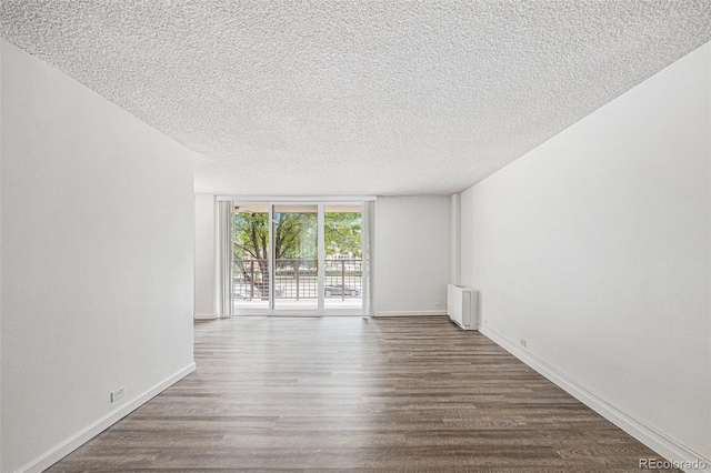 2225 Buchtel Blvd Unit 208, Denver, CO 80210 - spare room with radiator, wood finished floors, a textured ceiling, and a wall of windows