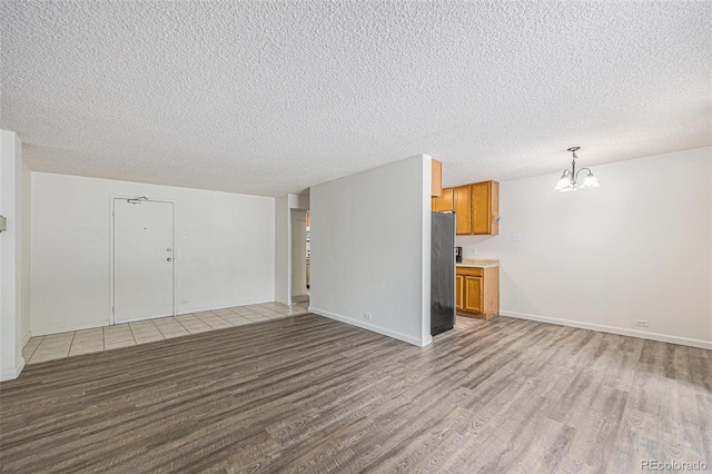 2225 Buchtel Blvd Unit 208, Denver, CO 80210 - unfurnished living room with wood finished floors, a chandelier, and a textured ceiling