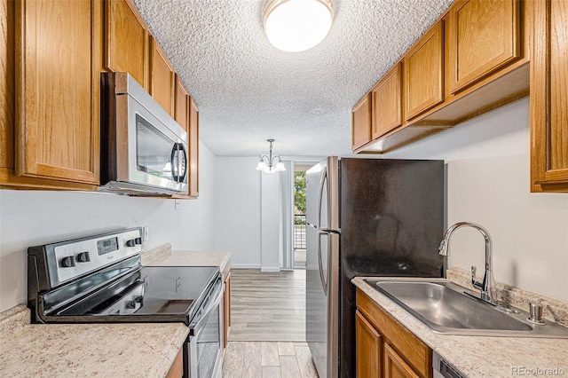 2225 Buchtel Blvd Unit 208, Denver, CO 80210 - kitchen featuring appliances with stainless steel finishes, brown cabinets, light wood-style floors, and a textured ceiling