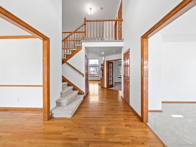 foyer entrance featuring baseboards, stairs, a high ceiling, and wood finished floors