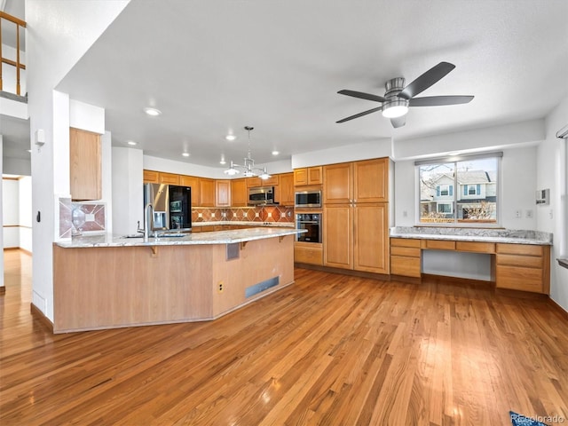 kitchen featuring light wood-type flooring, appliances with stainless steel finishes, a peninsula, decorative backsplash, and built in study area