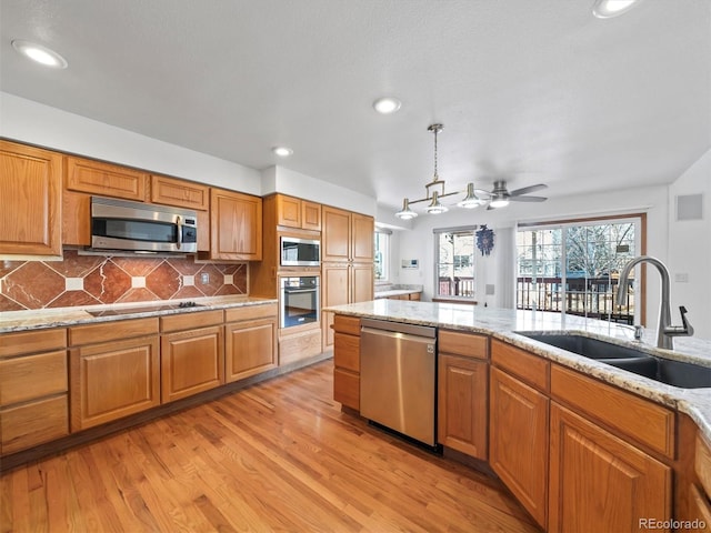 kitchen featuring a sink, brown cabinets, backsplash, and appliances with stainless steel finishes