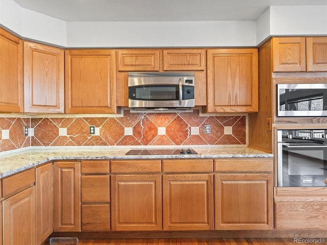 kitchen featuring light stone counters, tasteful backsplash, and appliances with stainless steel finishes