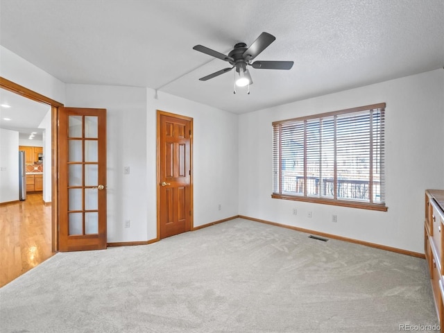 unfurnished bedroom featuring fridge, carpet flooring, baseboards, and visible vents