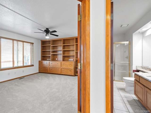 interior space with visible vents, ensuite bathroom, light tile patterned flooring, baseboards, and light colored carpet