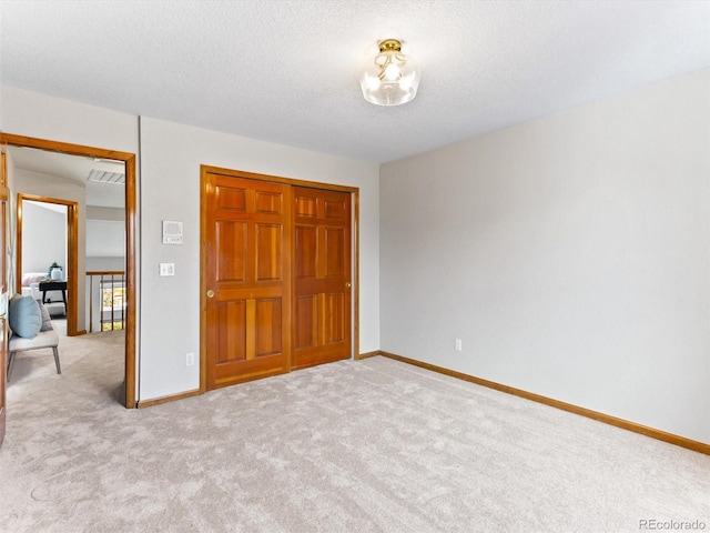 unfurnished bedroom with carpet flooring, a textured ceiling, and baseboards