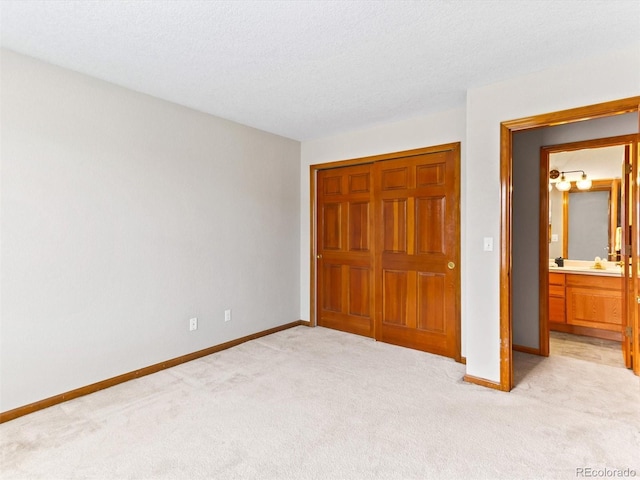 unfurnished bedroom with a textured ceiling, baseboards, a closet, and light carpet