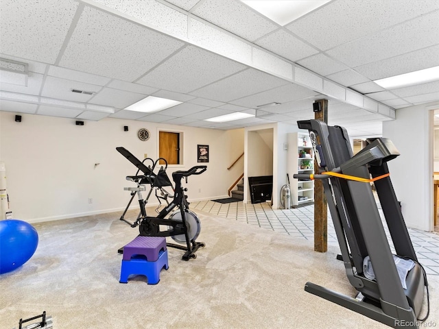 exercise area with a paneled ceiling, visible vents, baseboards, and carpet