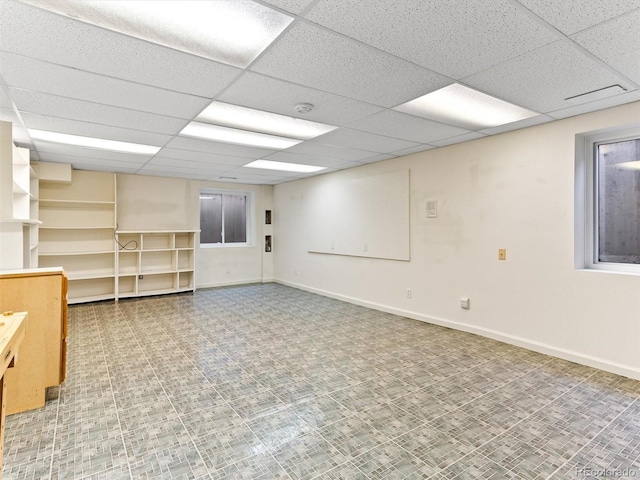 finished basement with a paneled ceiling and baseboards