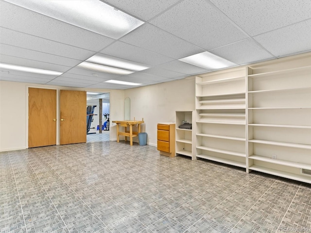 finished basement featuring a paneled ceiling and baseboards