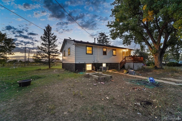 back house at dusk with central AC, a deck, and an outdoor fire pit