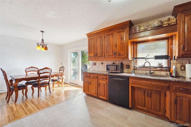 kitchen featuring hanging light fixtures, sink, light hardwood / wood-style flooring, backsplash, and black dishwasher