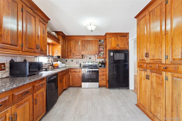 kitchen with light hardwood / wood-style floors, sink, decorative backsplash, black appliances, and dark stone countertops