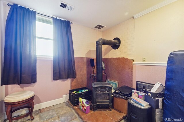 interior space with ornamental molding and a wood stove