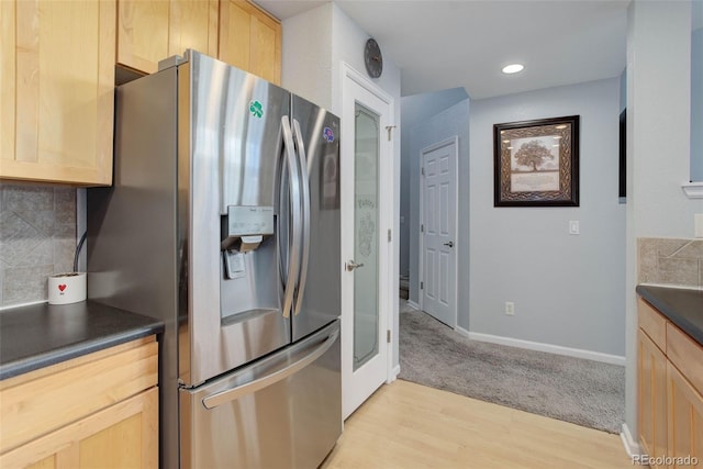 kitchen featuring light brown cabinetry, stainless steel fridge, light hardwood / wood-style flooring, and backsplash