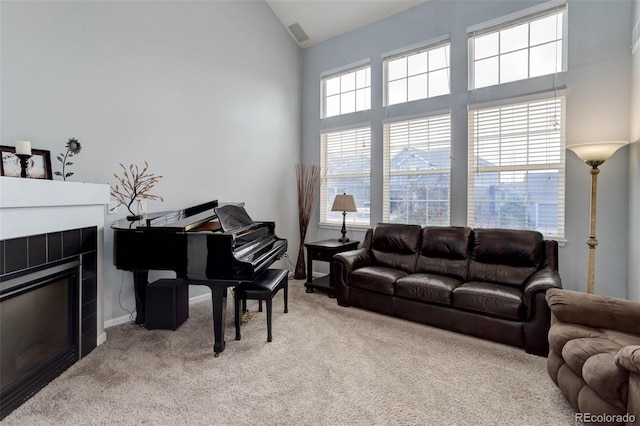 carpeted living room with a tiled fireplace and high vaulted ceiling