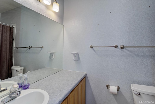 bathroom featuring vanity, curtained shower, and toilet