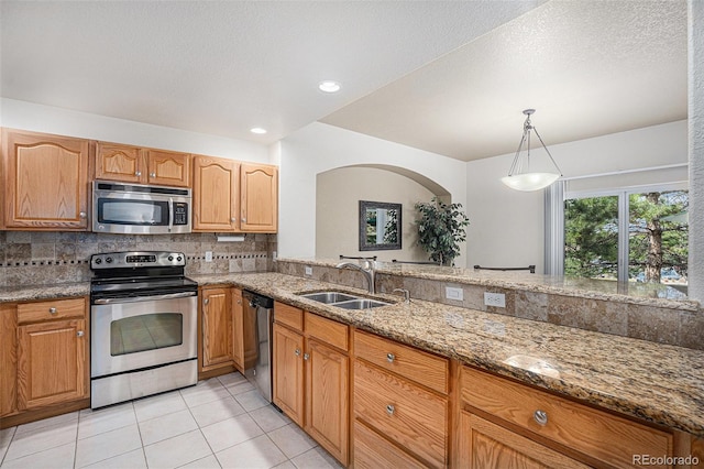 kitchen featuring decorative backsplash, light stone counters, a sink, appliances with stainless steel finishes, and light tile patterned floors