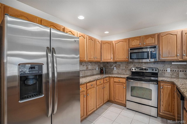 kitchen featuring light stone counters, appliances with stainless steel finishes, backsplash, and light tile patterned floors