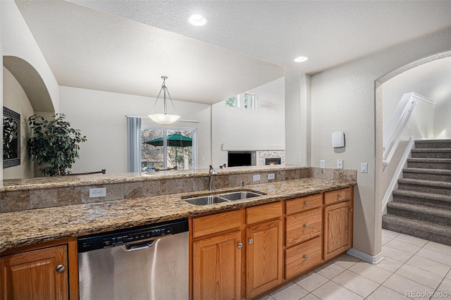 kitchen with a sink, dark stone countertops, dishwasher, and light tile patterned flooring