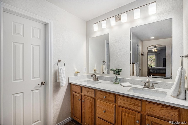 full bath featuring ensuite bathroom, a sink, a textured wall, and double vanity