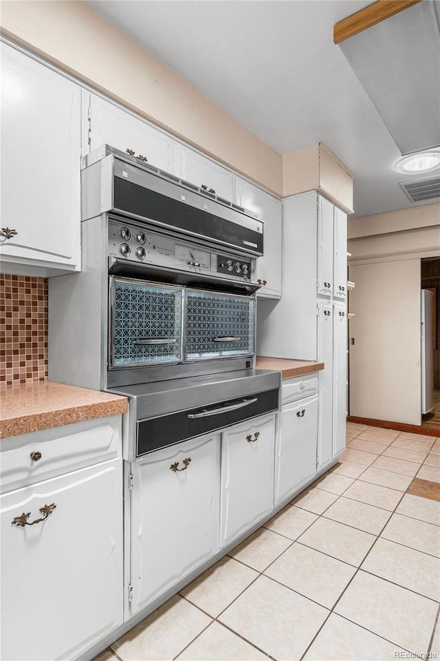 1280 Xanadu St, Aurora, CO 80011 - kitchen featuring light countertops, decorative backsplash, white cabinets, and light tile patterned floors
