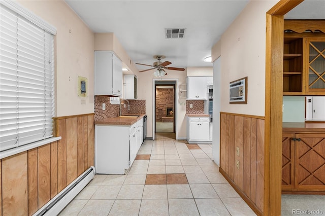1280 Xanadu St, Aurora, CO 80011 - kitchen featuring a ceiling fan, a wainscoted wall, a baseboard radiator, white cabinets, and decorative backsplash