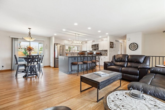 living area featuring baseboards, light wood-type flooring, and recessed lighting