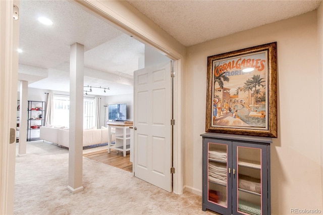 hall with light carpet and a textured ceiling