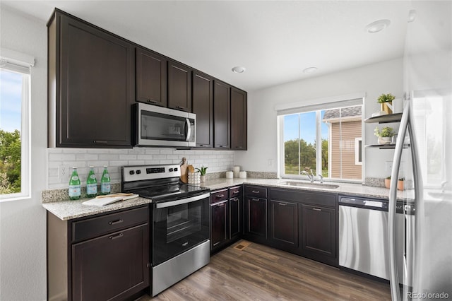 18645 E 54th Pl, Denver, CO 80249 - kitchen featuring stainless steel appliances, dark brown cabinetry, a sink, backsplash, and dark wood-style flooring