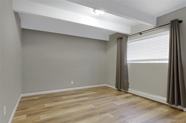 spare room with light wood-type flooring and beam ceiling