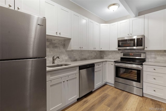 kitchen with backsplash, light hardwood / wood-style floors, sink, white cabinetry, and appliances with stainless steel finishes