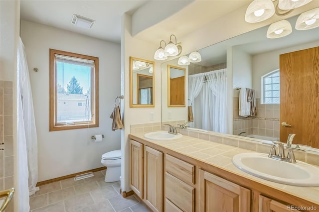 bathroom featuring a sink, visible vents, toilet, and double vanity