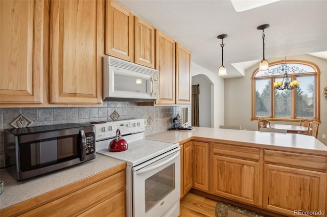 kitchen with tasteful backsplash, arched walkways, an inviting chandelier, light countertops, and white appliances
