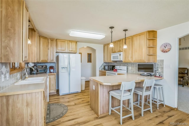 kitchen featuring arched walkways, a sink, white appliances, a peninsula, and backsplash