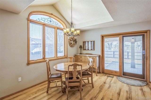 dining space featuring light wood-style flooring, a chandelier, baseboards, and vaulted ceiling