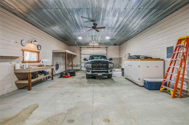 garage with wood walls, a ceiling fan, and electric panel