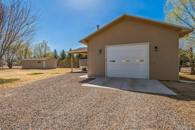 view of side of home with an outbuilding, a garage, stucco siding, and driveway