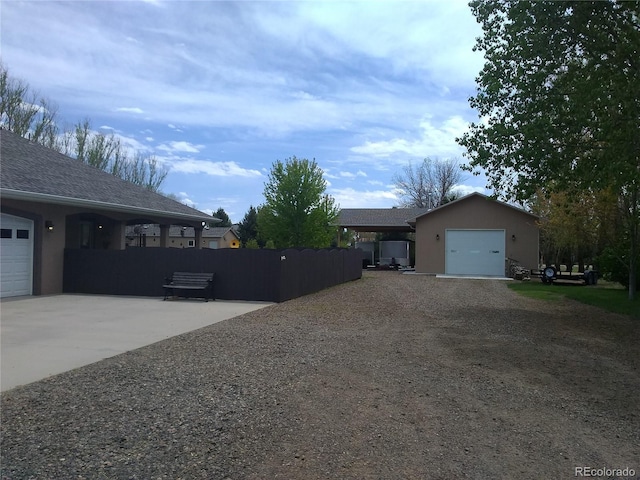 view of side of home featuring an attached garage, fence, driveway, and stucco siding