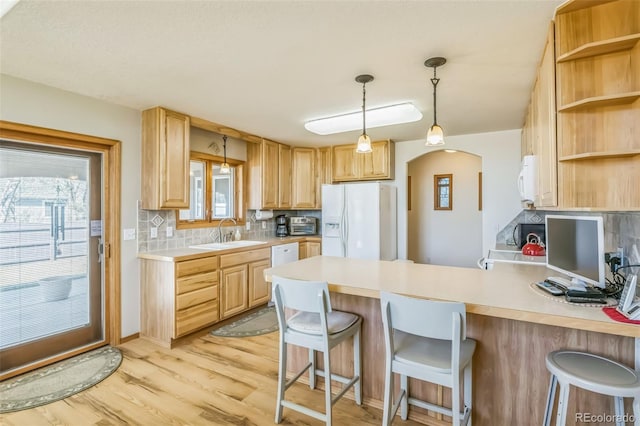 kitchen with white appliances, a peninsula, light countertops, backsplash, and a sink